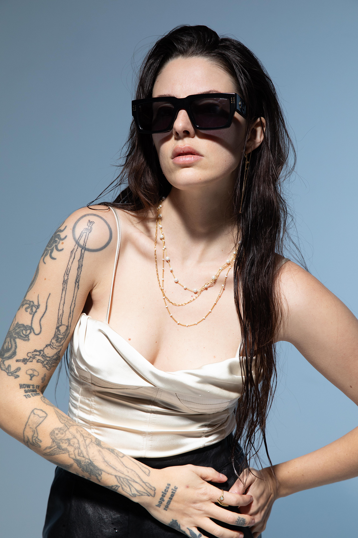 Woman wearing sunglasses and a white top against a blue background